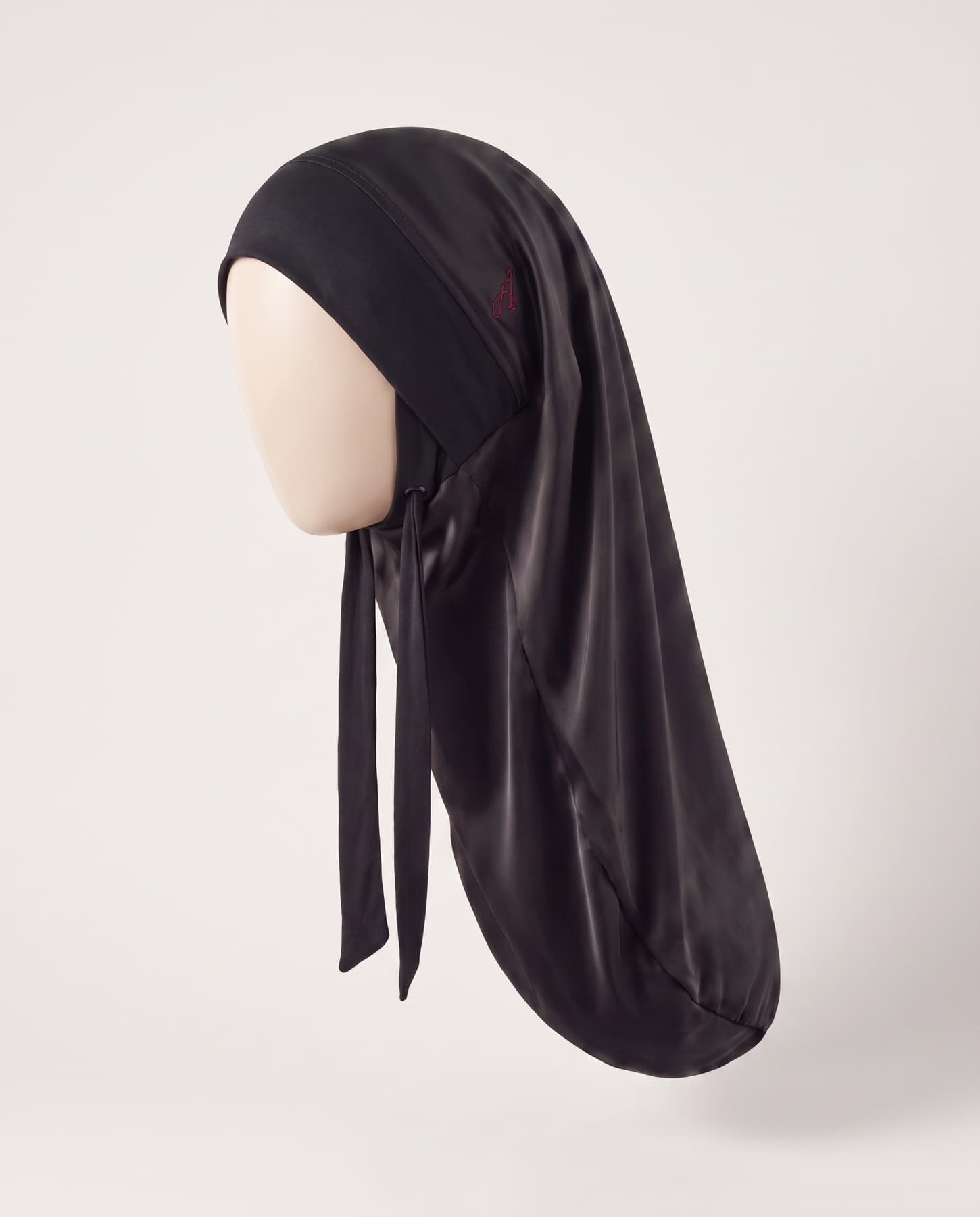Le Dessous de Voile Āriyah porté de profil sur une forme neutre sans visage, la bande sur le front et le long fourreau de soie qui enveloppe les cheveux